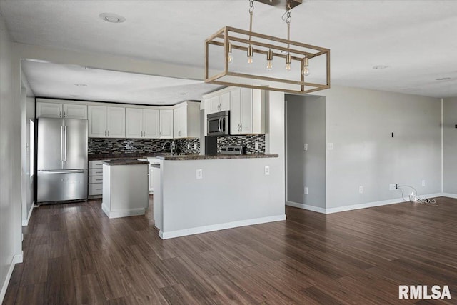 kitchen with white cabinets, dark hardwood / wood-style flooring, stainless steel appliances, and tasteful backsplash