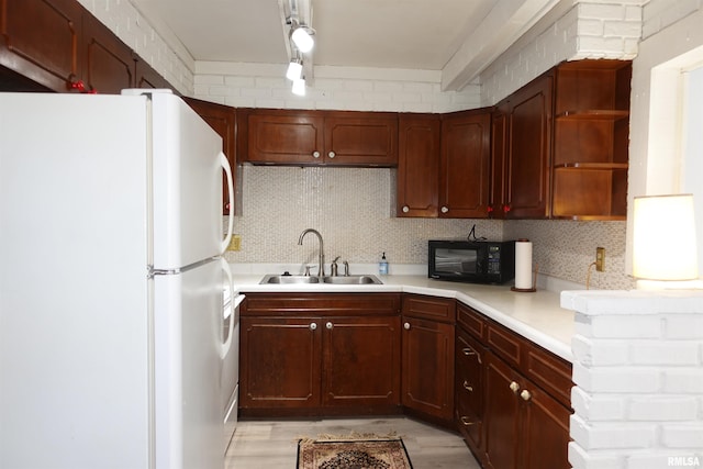 kitchen with decorative backsplash, white fridge, light hardwood / wood-style floors, and sink