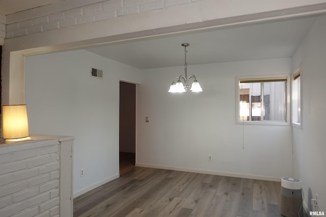 unfurnished dining area featuring a chandelier and hardwood / wood-style flooring