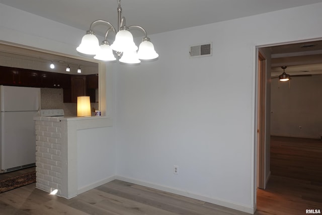 unfurnished dining area featuring light hardwood / wood-style flooring and ceiling fan with notable chandelier