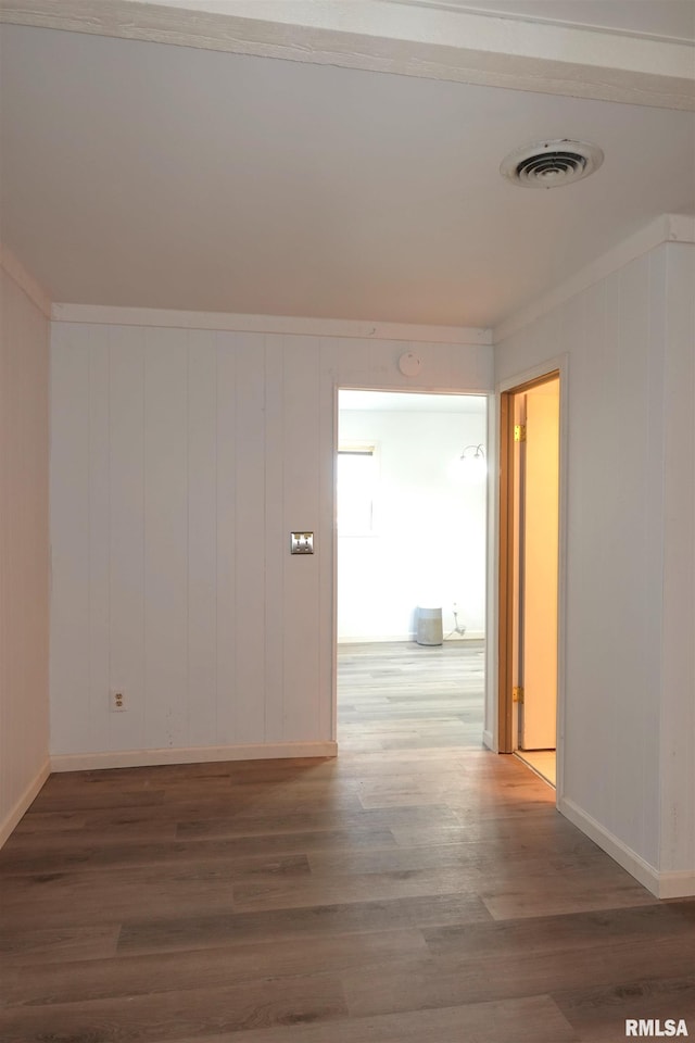 empty room with dark hardwood / wood-style floors and crown molding