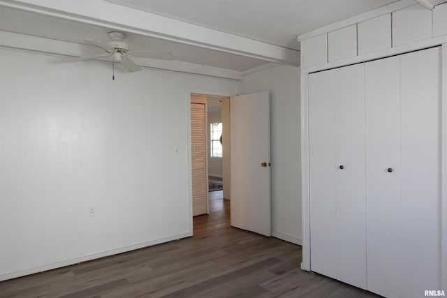 unfurnished bedroom with a closet, ceiling fan, hardwood / wood-style floors, and beamed ceiling