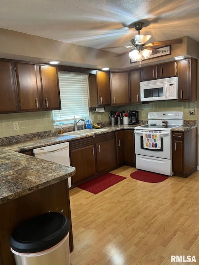 kitchen with decorative backsplash, light wood-type flooring, dark brown cabinets, white appliances, and ceiling fan