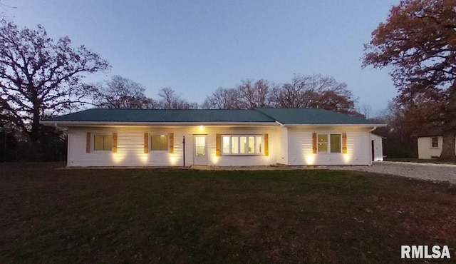 ranch-style house featuring gravel driveway and a front lawn