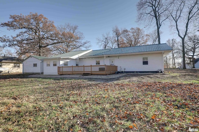 rear view of house with a deck, metal roof, and a yard