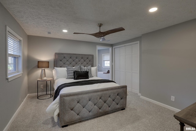 bedroom with a closet, carpet flooring, a textured ceiling, and baseboards