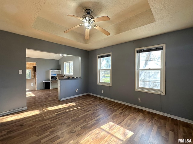 spare room with a textured ceiling, plenty of natural light, dark wood-type flooring, and ceiling fan