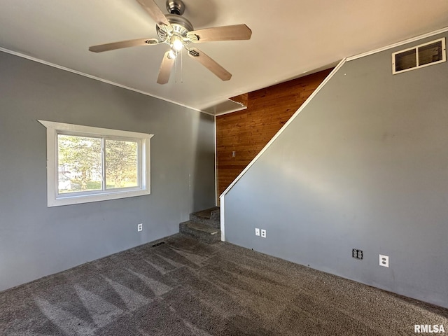 carpeted spare room featuring ceiling fan, crown molding, and wood walls