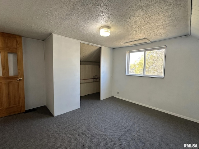 unfurnished bedroom featuring a textured ceiling, dark carpet, a closet, and vaulted ceiling