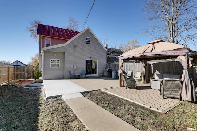 rear view of property with a gazebo, an outdoor living space, and a patio area