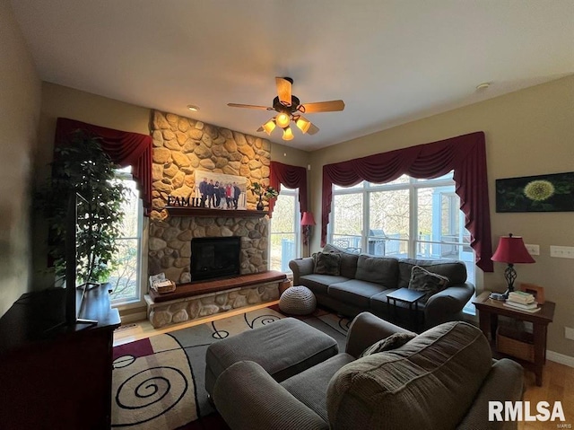 living room featuring hardwood / wood-style floors, a stone fireplace, ceiling fan, and a healthy amount of sunlight