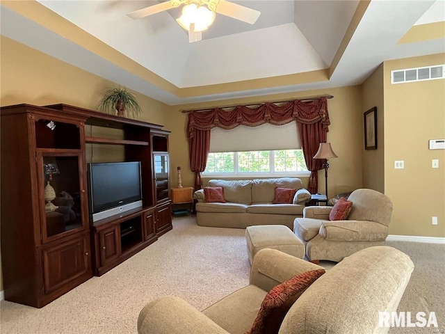 carpeted living room with a tray ceiling and ceiling fan