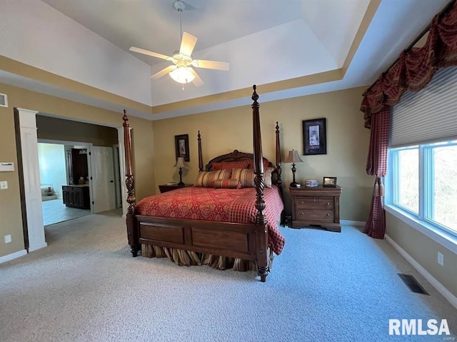 bedroom with light colored carpet, a raised ceiling, and ceiling fan