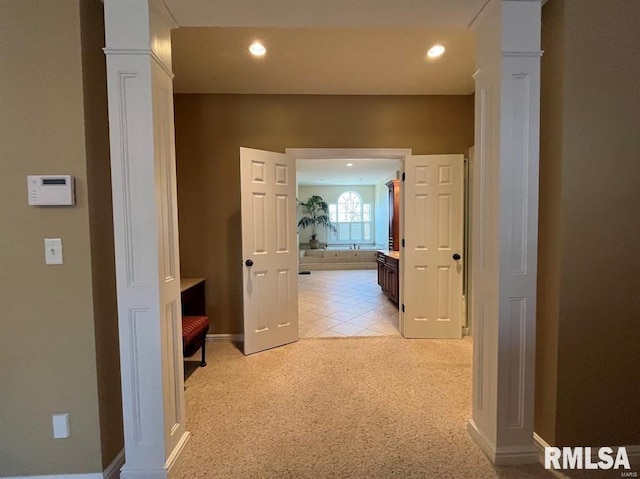 hall featuring decorative columns and light carpet