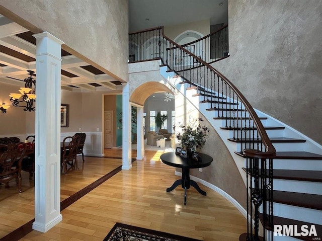 entryway with coffered ceiling, beamed ceiling, a notable chandelier, decorative columns, and hardwood / wood-style flooring