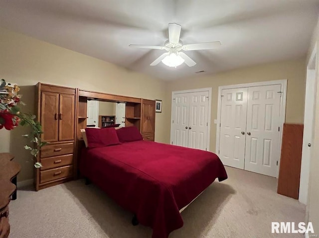 carpeted bedroom featuring ceiling fan and multiple closets