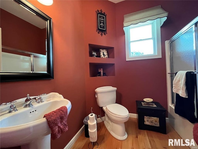 bathroom featuring sink, wood-type flooring, a shower with shower door, and toilet