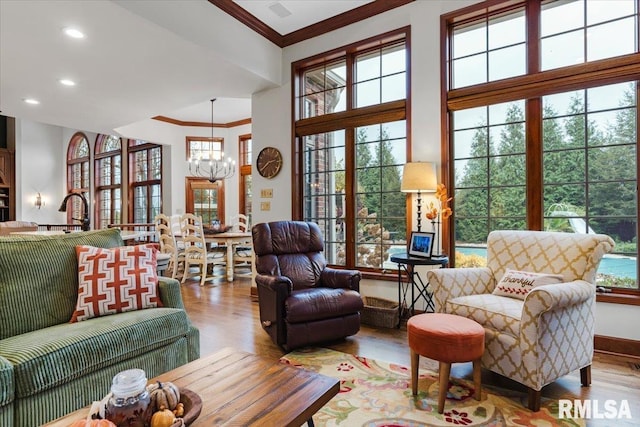 living room with a chandelier, light wood-type flooring, crown molding, and sink