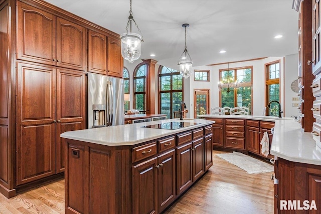 kitchen with stainless steel refrigerator with ice dispenser, sink, pendant lighting, light hardwood / wood-style flooring, and an island with sink