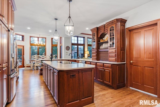 kitchen featuring refrigerator with ice dispenser, a kitchen island with sink, hanging light fixtures, and light hardwood / wood-style floors