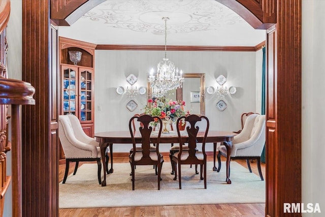 dining area featuring an inviting chandelier, light hardwood / wood-style flooring, and crown molding