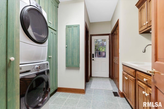 laundry room with cabinets, light tile patterned floors, stacked washer / dryer, and sink