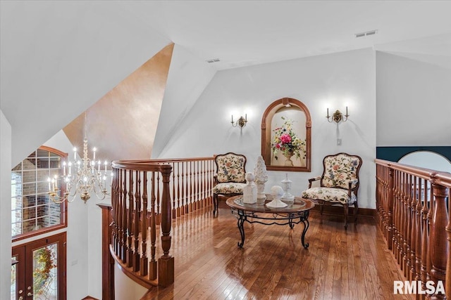 living area with hardwood / wood-style flooring, lofted ceiling, and an inviting chandelier