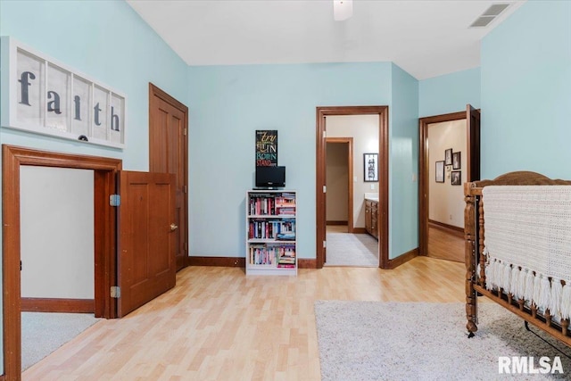 bedroom with ensuite bathroom, light hardwood / wood-style flooring, and ceiling fan