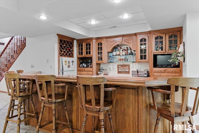 bar featuring tasteful backsplash, a drop ceiling, and white fridge