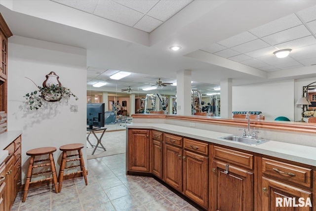 kitchen featuring kitchen peninsula, ceiling fan, sink, and a drop ceiling