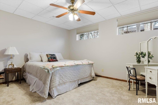 bedroom with a paneled ceiling, light colored carpet, and ceiling fan