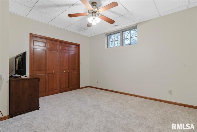 unfurnished bedroom featuring a closet, a paneled ceiling, light colored carpet, and ceiling fan