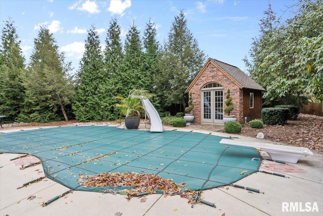 view of swimming pool featuring a patio area, a diving board, an outdoor structure, and a water slide