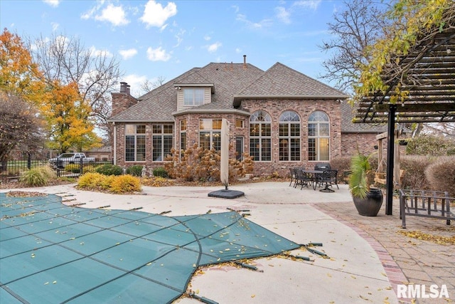 rear view of house featuring a covered pool and a patio area