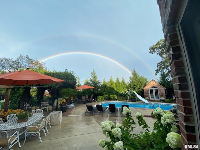 view of pool with an outdoor structure, a patio, and a water slide