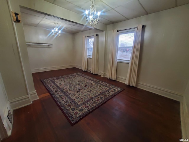 interior space featuring a drop ceiling, dark hardwood / wood-style flooring, and an inviting chandelier