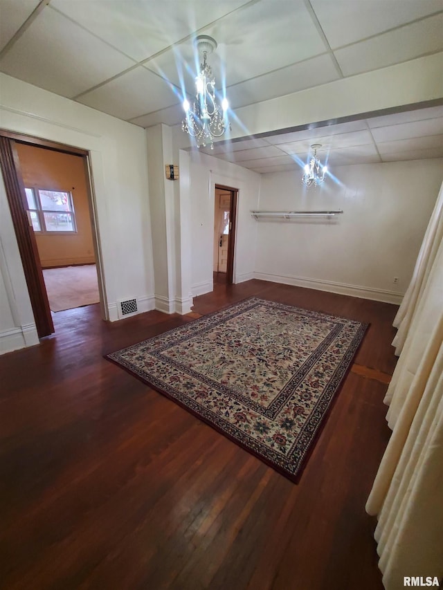 dining space featuring a paneled ceiling, dark wood-type flooring, and a notable chandelier