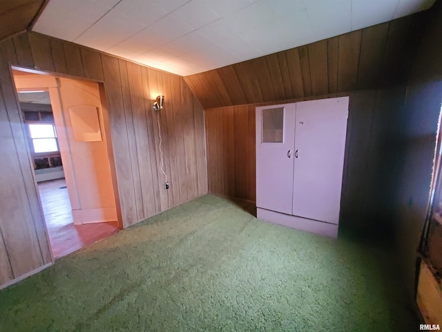 additional living space featuring carpet flooring, wood walls, and vaulted ceiling