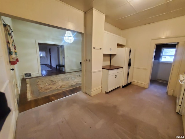 interior space with white cabinets, light colored carpet, and white refrigerator