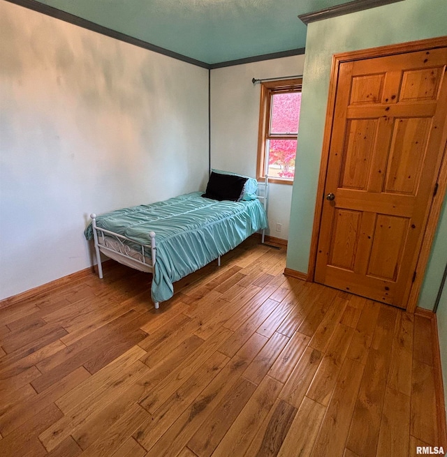 unfurnished bedroom featuring crown molding and light hardwood / wood-style flooring