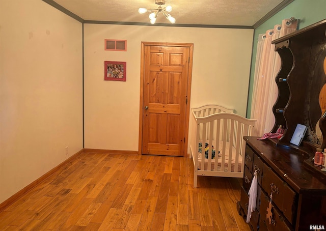 bedroom with crown molding, a chandelier, a textured ceiling, and light wood-type flooring