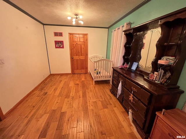 interior space with a textured ceiling, light hardwood / wood-style flooring, and crown molding