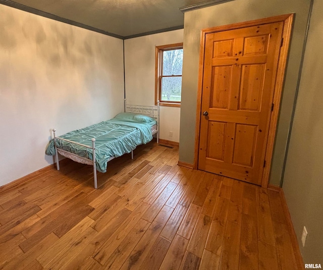 unfurnished bedroom featuring crown molding and light hardwood / wood-style floors