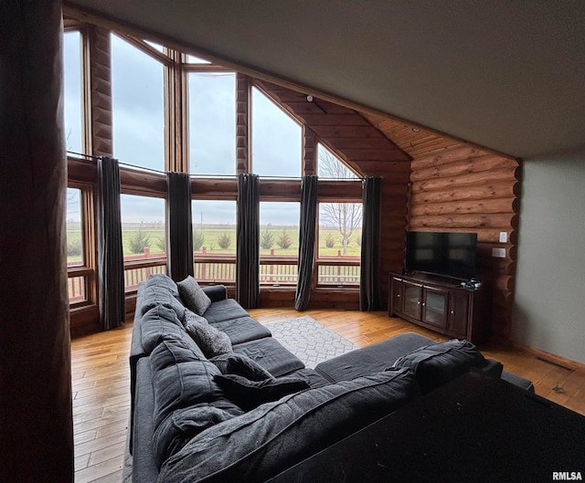 living room featuring light hardwood / wood-style floors, log walls, and vaulted ceiling