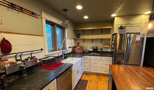 kitchen with hanging light fixtures, stainless steel appliances, butcher block countertops, light hardwood / wood-style floors, and white cabinets