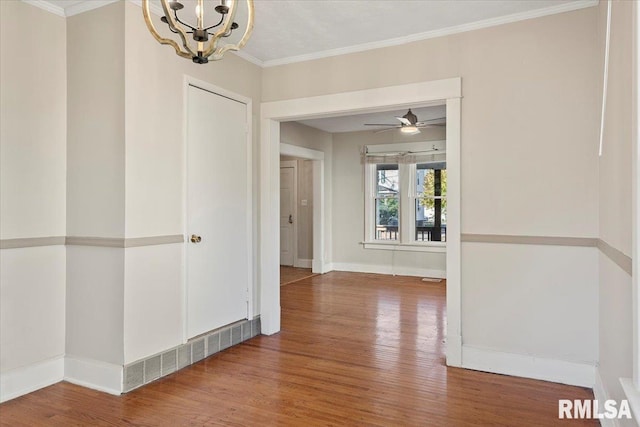 hallway with wood-type flooring, an inviting chandelier, and crown molding