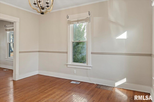 spare room featuring wood-type flooring, an inviting chandelier, and ornamental molding