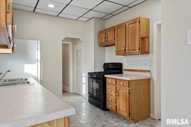 kitchen featuring a paneled ceiling, decorative backsplash, black range with gas stovetop, and sink