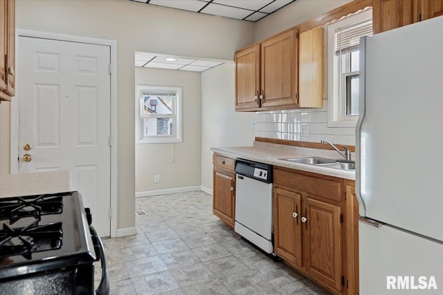 kitchen with sink, white appliances, a healthy amount of sunlight, and backsplash