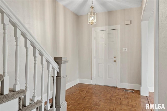 foyer entrance with an inviting chandelier and parquet flooring